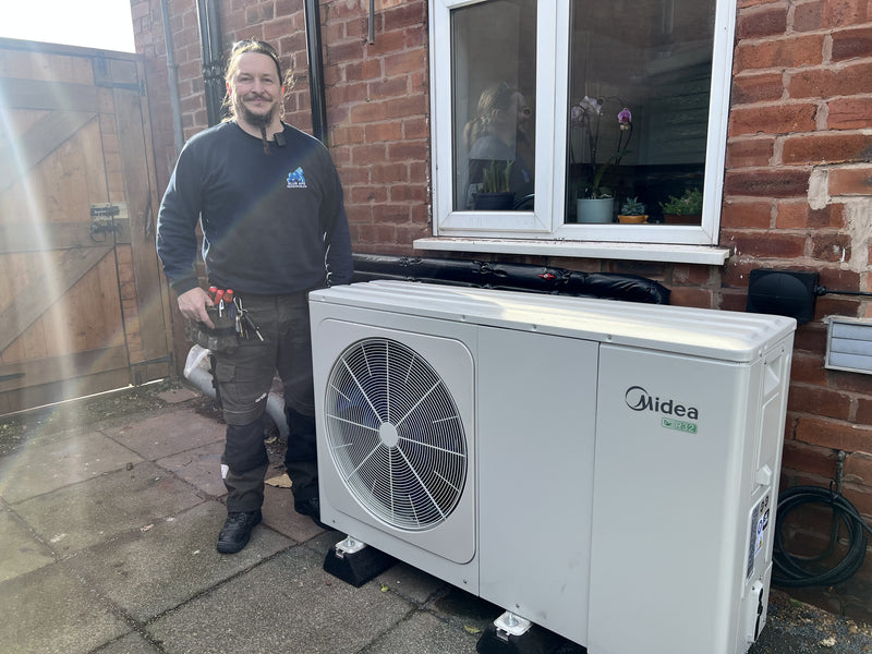 Installers fitting an air source heat pump at a UK home